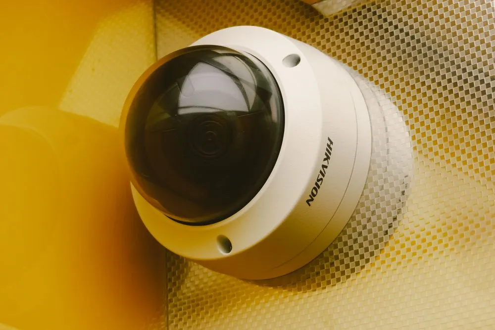 Sarı duvara monte edilmiş beyaz Hikvision dome IP kamera